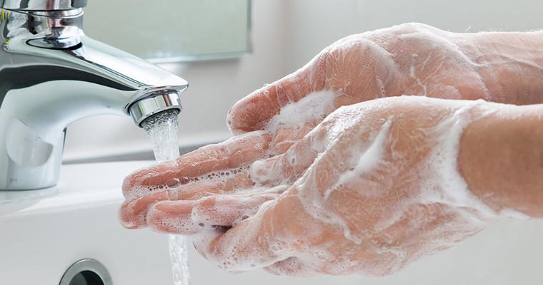 Soapy hands being scrubbed under a faucet with running water