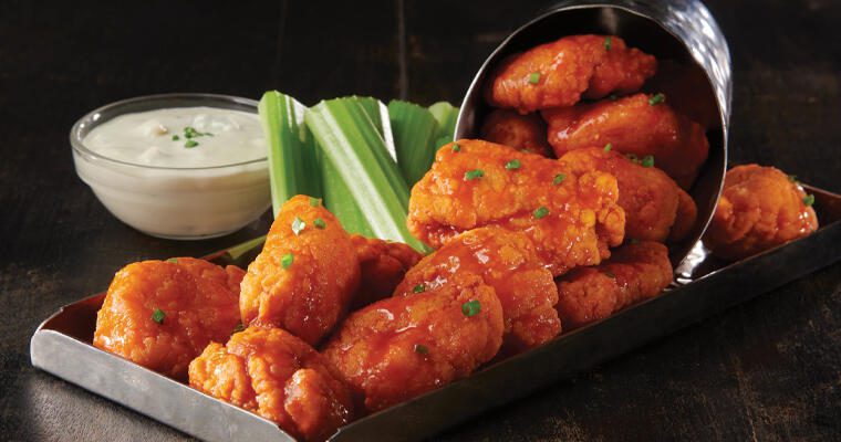 A hot chicken wings and celery appetizer with a cup of ranch dip