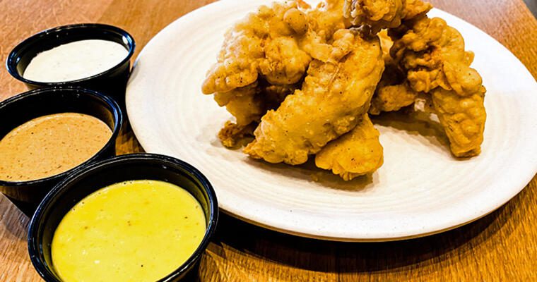 Cream City Cluckery chicken tenders on a white plate with three dipping sauces