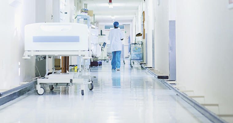 A doctor walks through a white hallway in healthcare facility