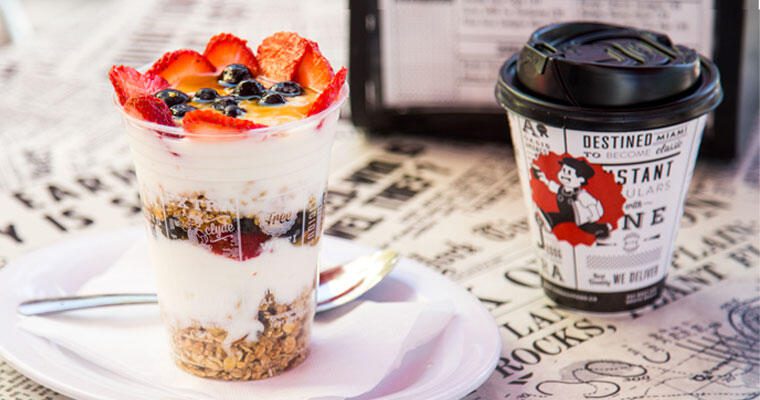 The Daily Creative Food Co. parfait on a white plate with a cup of coffee