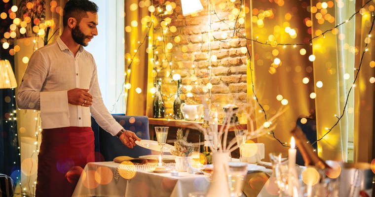 A server prepares a festive holiday table for guests