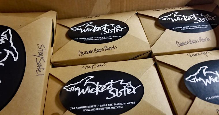 To-go carryout boxes with The Wicked Sister restaurant logo