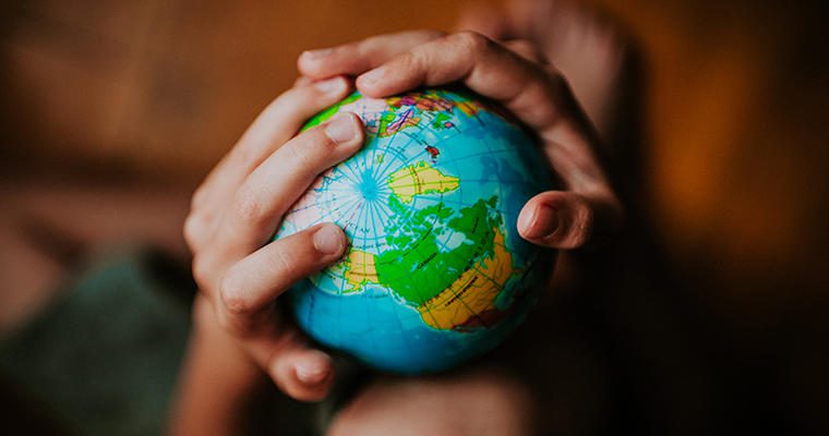 Children's hands hold a small globe