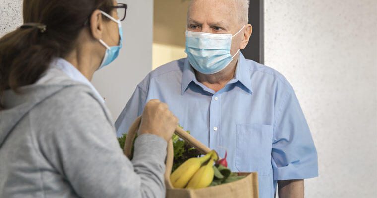 A senior receives a bag of groceries from a healthcare delivery service
