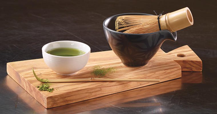 Matcha in a cup with bamboo whisk