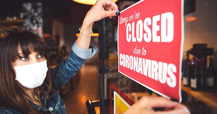A restaurant worker hangs a "Closed due to Coronoavirus" sign on the door