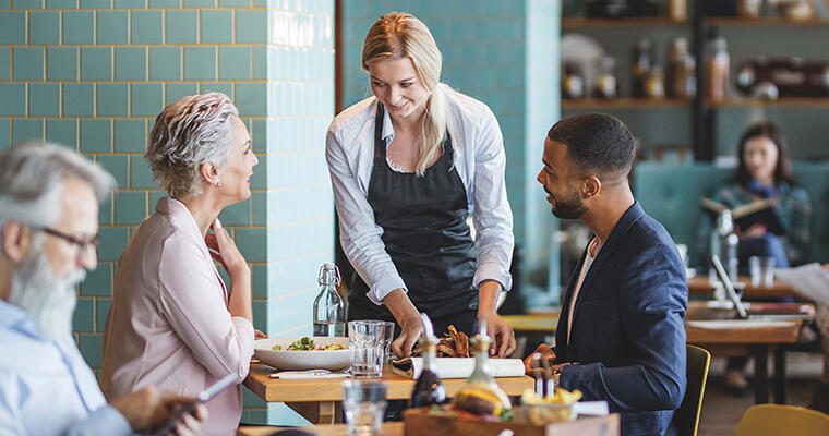 A restaurant server discusses menu items with a customer