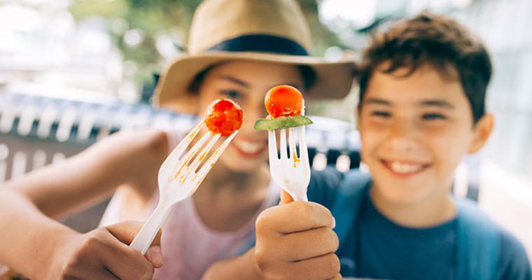 Children holding fork with cherry tomato