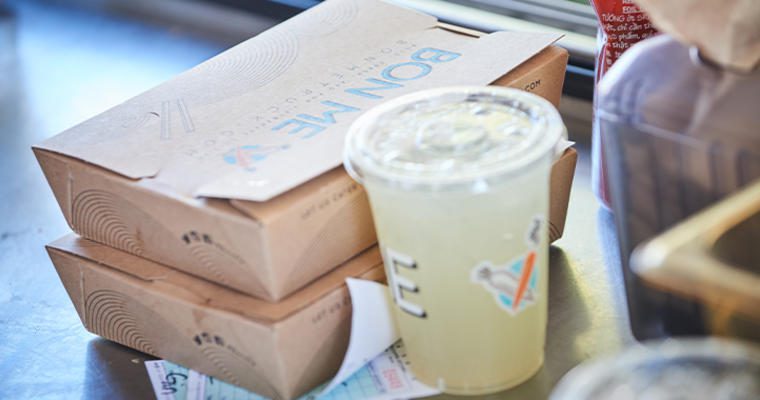 Two restaurant to go boxes with a to go cup of lemonade