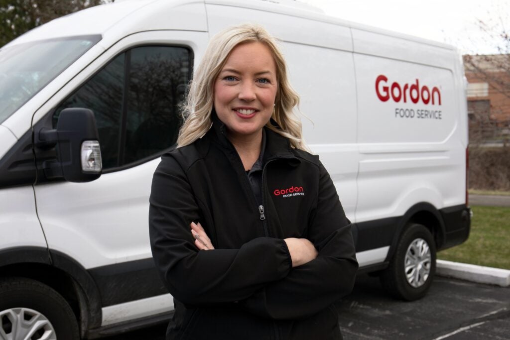 A Women at Gordon Food Service posing for a photo in front of an Express-Delivery Van.