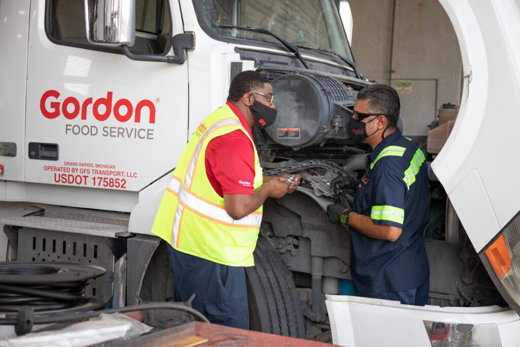 Two men in the distribution center in Houston, TX chatting next to a delivery truck.