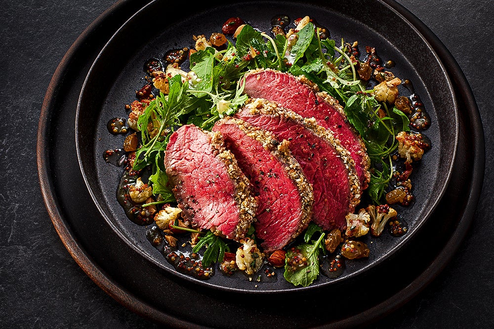 Slices of beef cut thinly, served on greens and cooked cauliflower