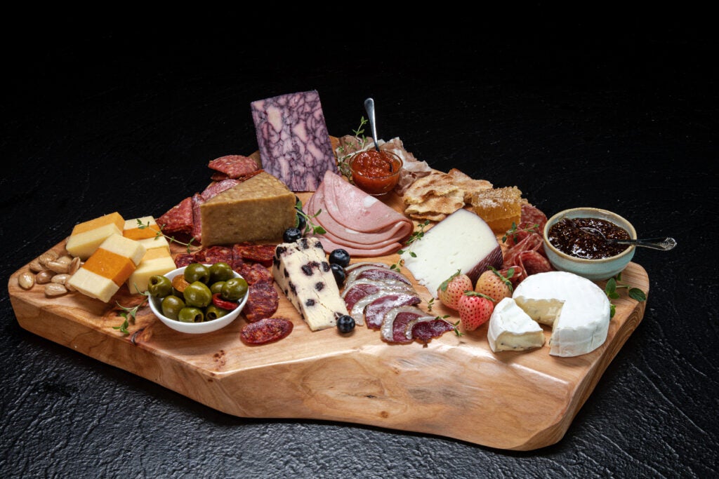 a wooden platter filled with cheese and meats.