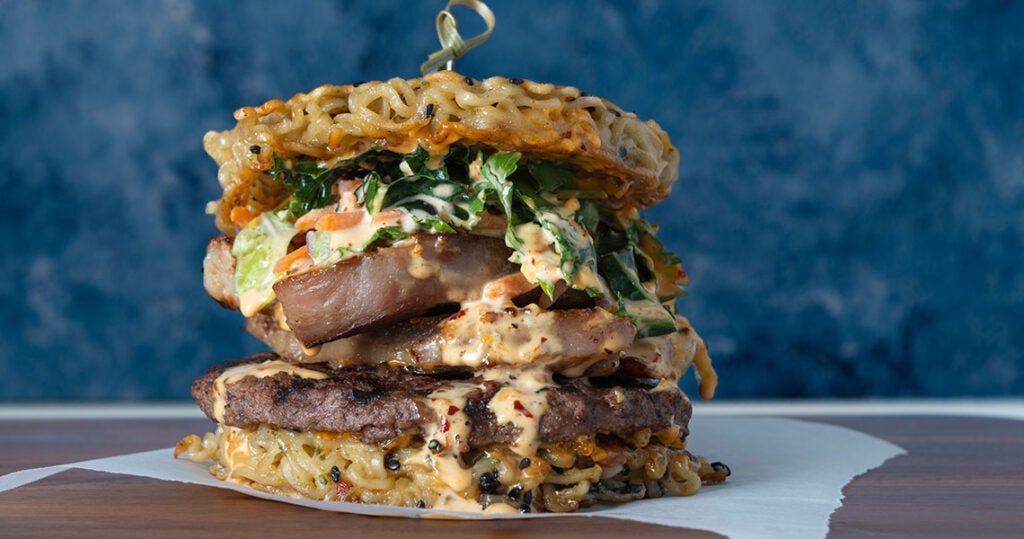 chao cooking burger with fried noodle bun, global flavors inspires new dishes.