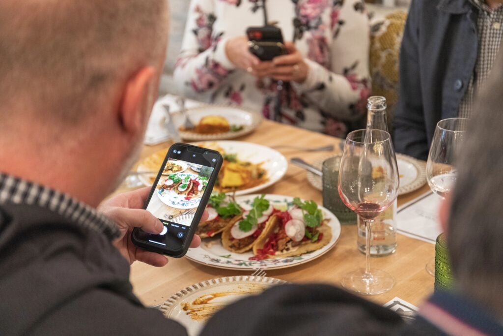 A man taking a picture of his meal on the restaurant table top before eating it