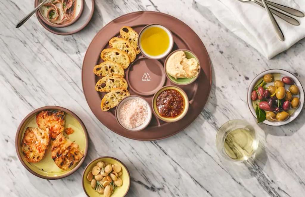 Sharing platting with baked bread and dips centered with other shareable dishes on a table top