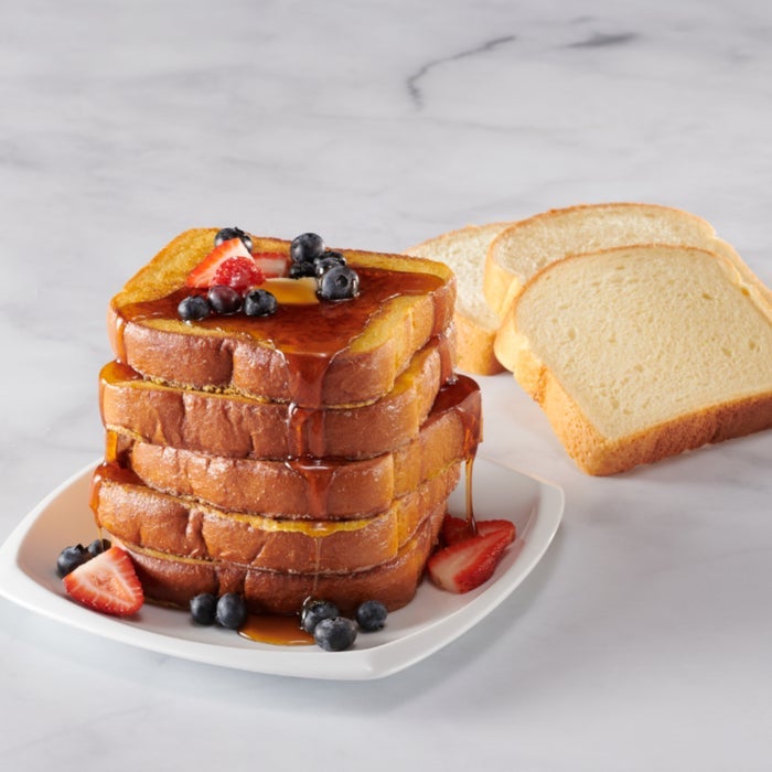 French Toast brioche bread stack, served on a plate with berries and syrup on top.