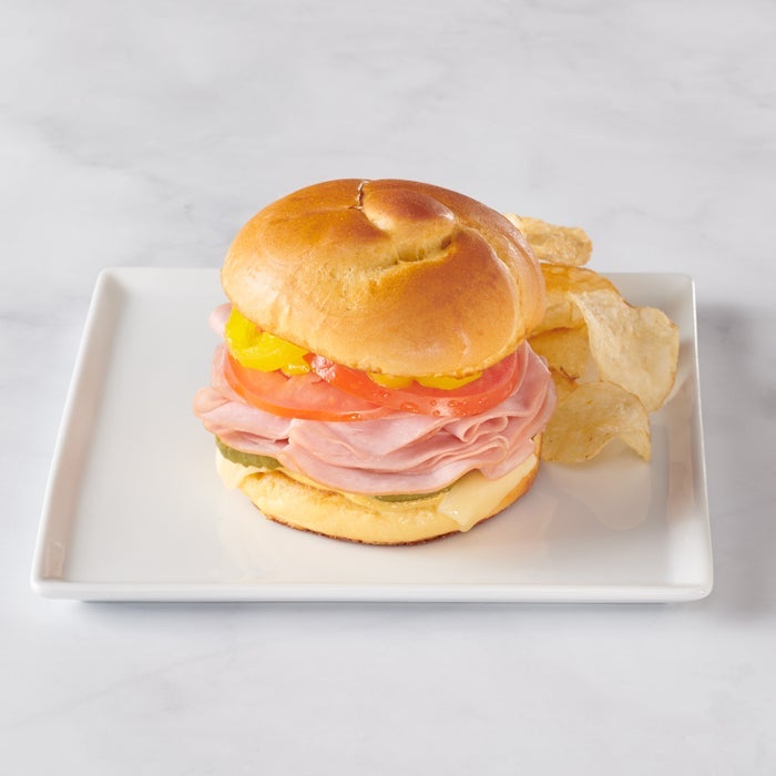 A brioche knot but on a white square plate with chips next to the sandwich.