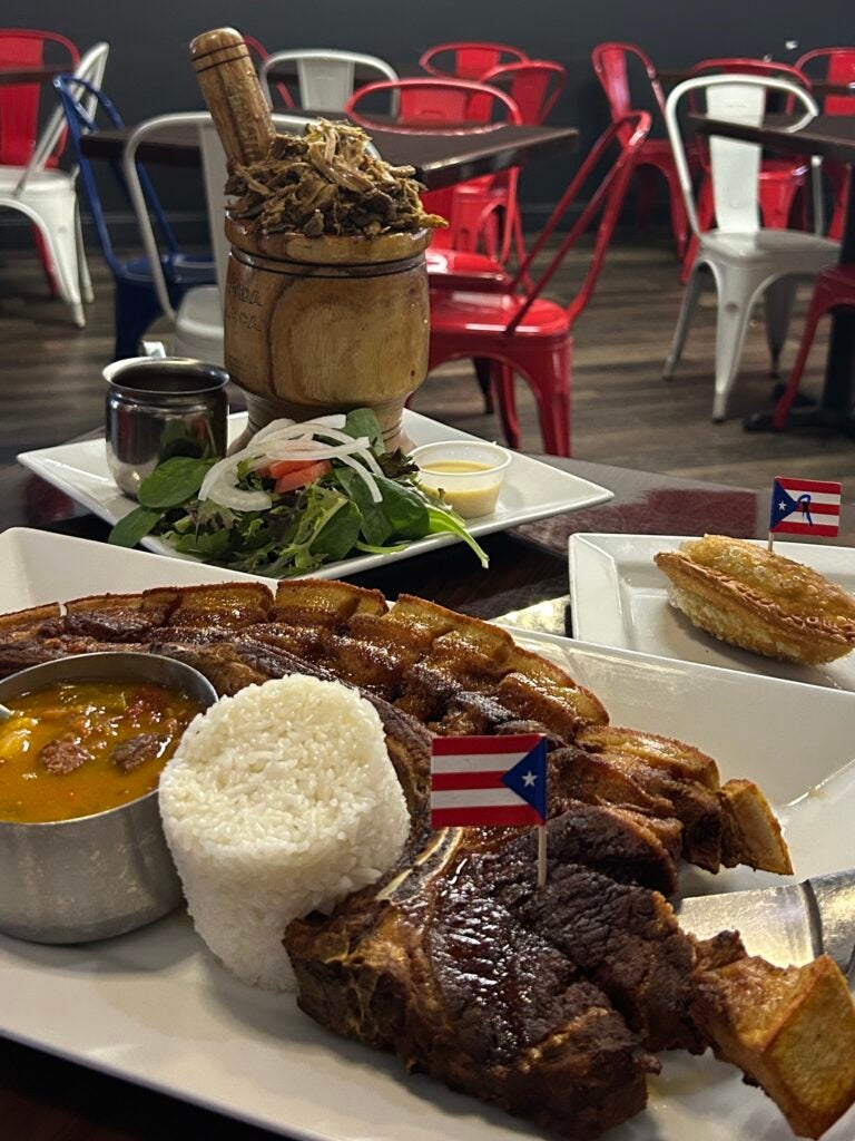 Puerto Rican feast with mofongo, fried pork chops, rice, beans, and small Puerto Rican flags.