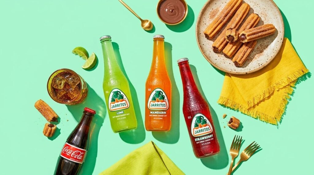Bottles of Jarritos sodas and Coca-Cola served alongside chocolate-filled churros on a bright green background.
